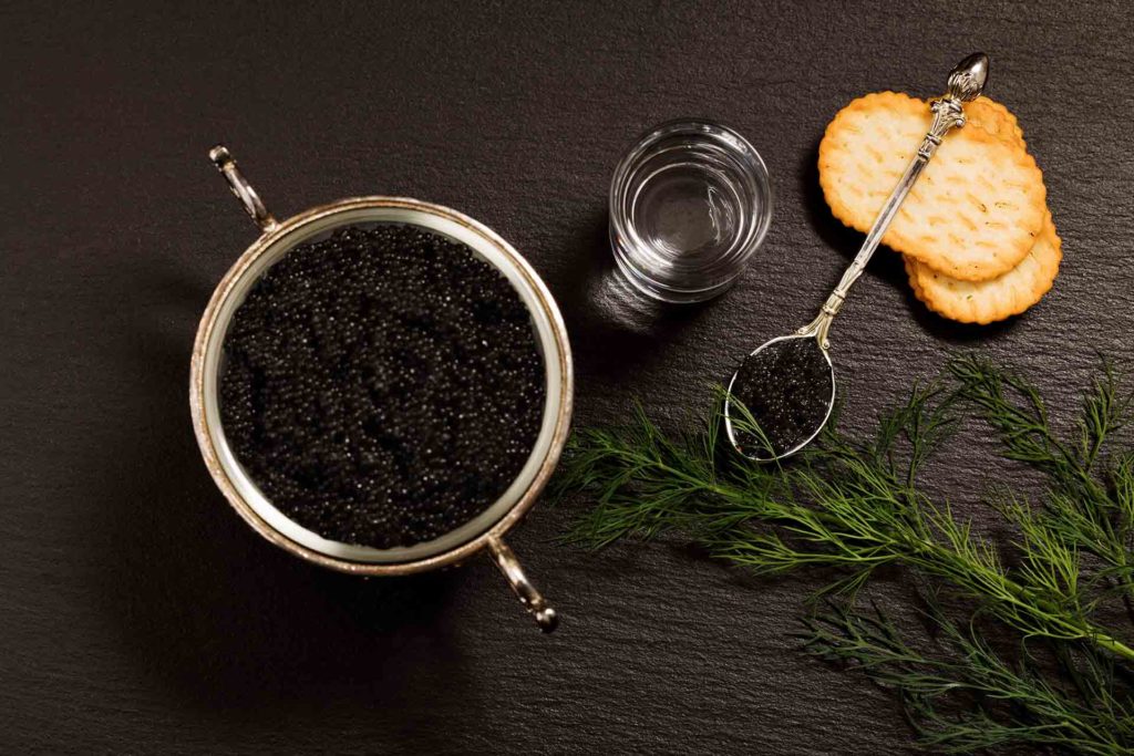 Black caviar served on crackers with vodka and additives