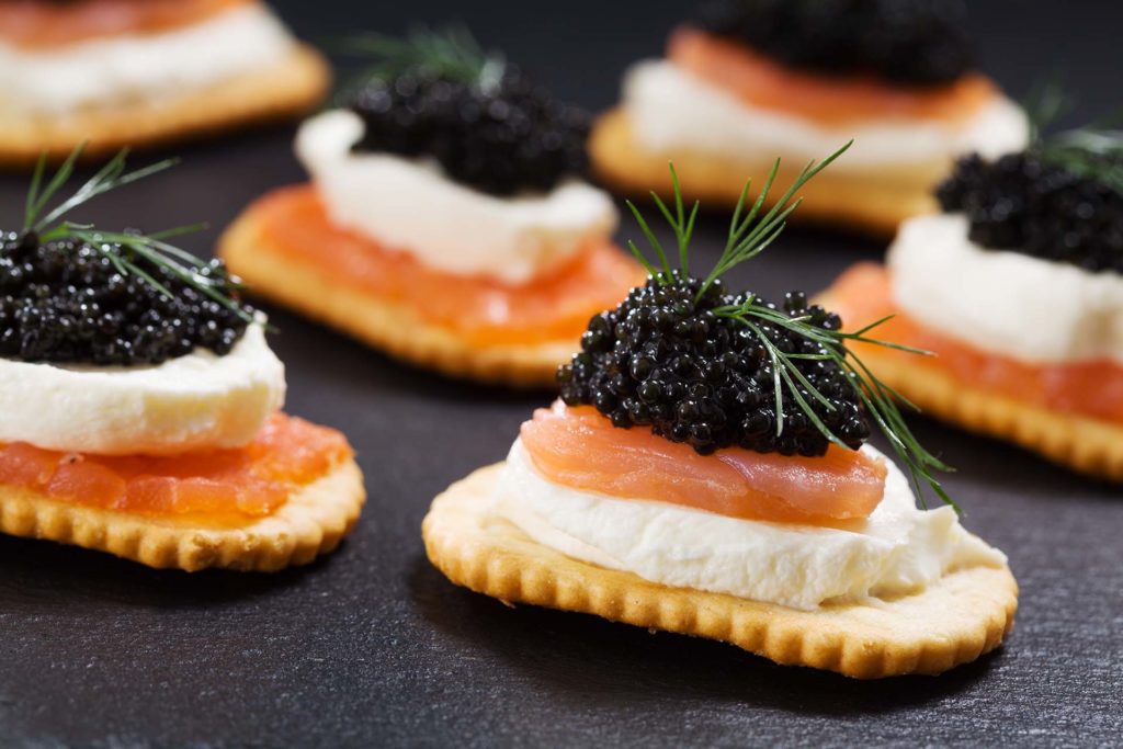 Black caviar served on crackers with salmon and cream cheese.