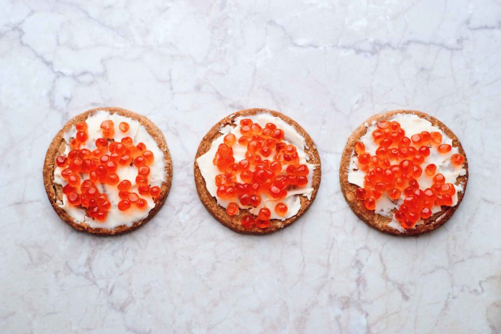 Three mini pancakes with caviar and cream on top