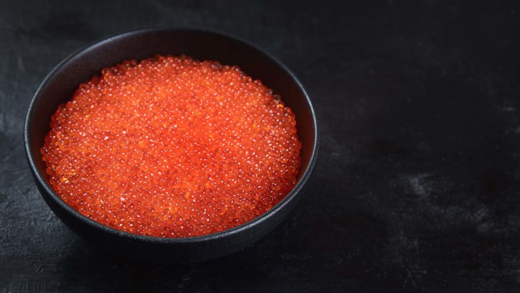 Salmon roe. Red caviar on black background. Image with copy space